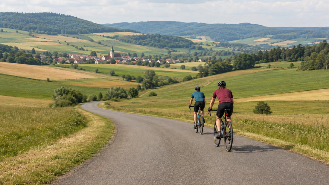 Zwei Radfahrer auf einer ruhigen Landstraße in sommerlicher Hügellandschaft